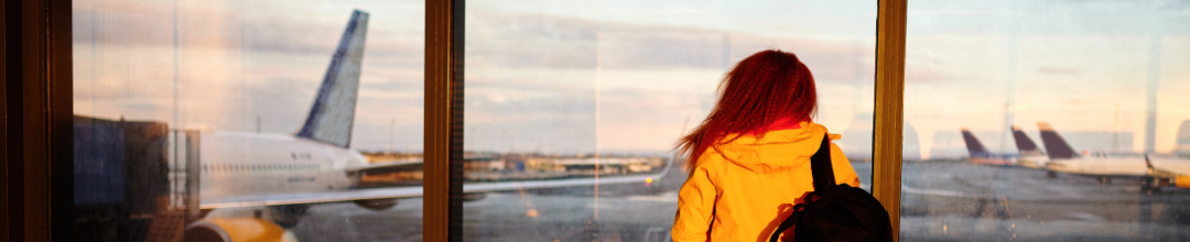 A young woman looking out the window at an airport tarmac