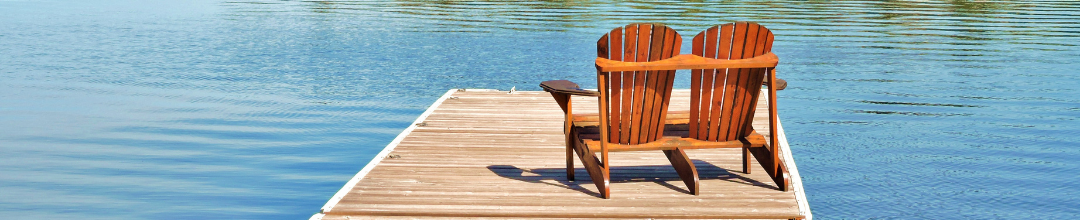 A pair of Adirondack chairs on a dock on the lake