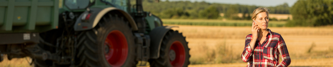 Female farmer looking out over crop with tractor in background