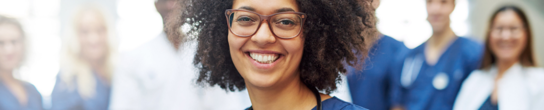 A doctor smiling in the foreground with her crew in the background