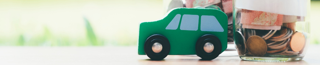 Paper car with piggy bank in background