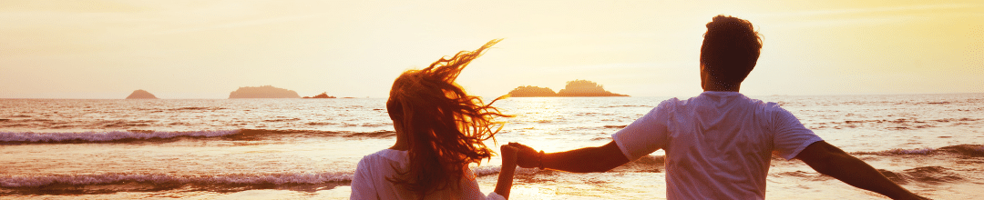 Two people running into a beach sunset